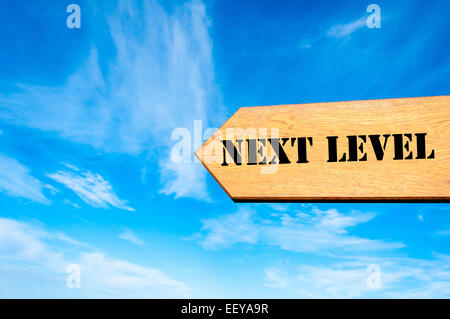 Holz Pfeilzeichen gegen strahlend blauen Himmel mit Next Level Nachricht, Fortschritt Konzeptbild Stockfoto