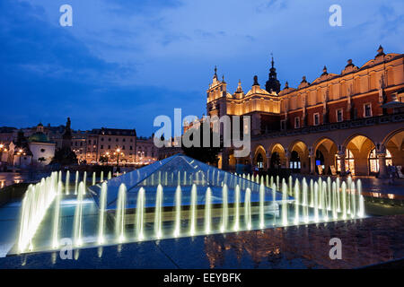 Polen, Malopolskie, Krakau, beleuchtete Brunnen und Tuchhallen in der Abenddämmerung Stockfoto