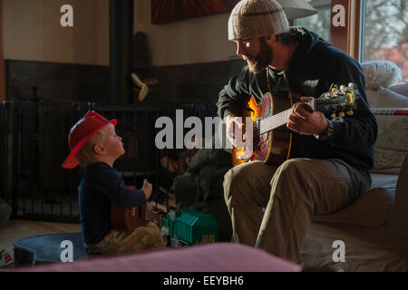 Junge (4-5), sein Vater spielte Gitarre hören Stockfoto