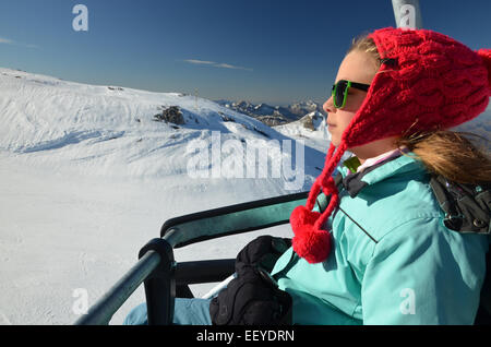 Junges Mädchen mit roten Winter Hut und Sonnenbrille auf Sessellift am Ski resort Pierre Saint-Martin in atlantischen Pyrenäen, weiße sno Stockfoto