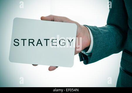 ein junger Geschäftsmann zeigt ein Schild mit dem Wort Strategie geschrieben Stockfoto