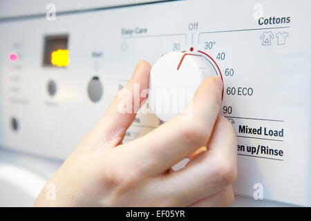 Frau Wahl kühlere Temperatur auf Waschmaschine um Energie zu sparen Stockfoto