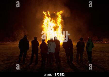 Silhouette Menschen stehen gerade eine organisierte Lagerfeuer im Bught Park, Inverness, Hochland.  Die Flammen erreichen hoch. Stockfoto