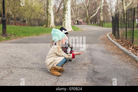 Kleine Mädchen feeds ein Eichhörnchen in den Central Park, New York, USA Stockfoto