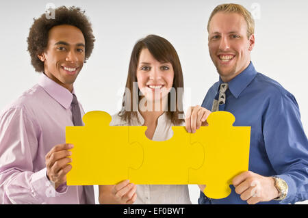 Drei Geschäftsleute halten Puzzleteile Stockfoto