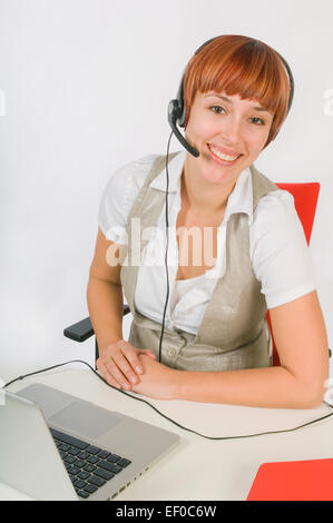 Frau trägt Kopfhörer beim Sitzen am Schreibtisch Stockfoto