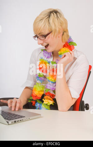 Blonde Frau sitzt am Schreibtisch tragen ein lei Stockfoto