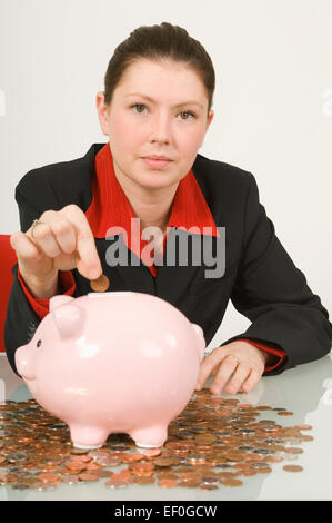 Geschäftsfrau, die setzen eines Cent in ein Sparschwein Stockfoto