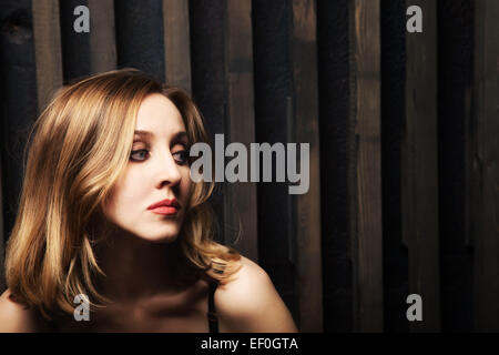 Studio-Porträt einer jungen Frau gegen eine Holzwand Stockfoto
