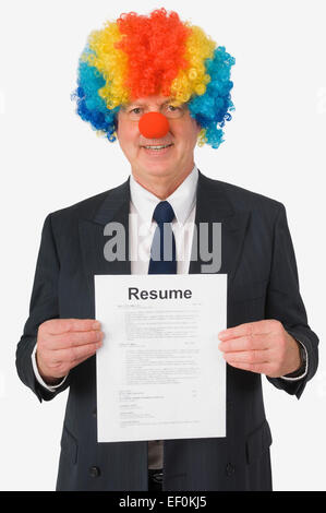 Geschäftsmann trägt Clownsnase und Perücke und hält Lebenslauf Stockfoto