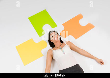 Frau liegend am Boden neben übergroßen Puzzleteile Stockfoto