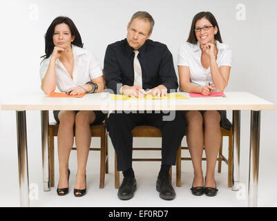 Drei Personen sitzen am Schreibtisch Stockfoto