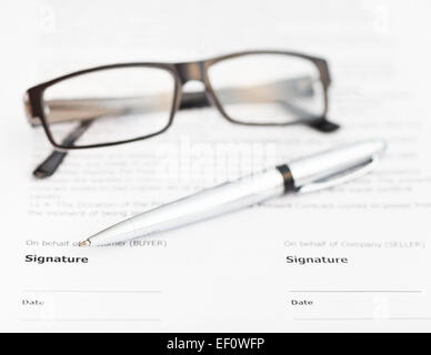 Silberstift und Brillen auf Seite der Unterschrift des Kaufvertrages Stockfoto