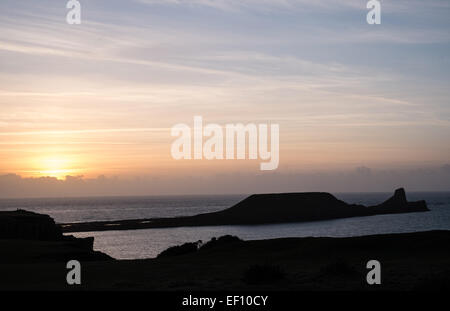 Wanderer-Silhouette bei Sonnenuntergang an einem bitter kalten, sonnigen und windigen Tag in Wurm Kopf, Rhossili Strand Bucht, Halbinsel Gower, Wales, UK, Stockfoto