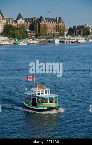 Eine Hafen Fähre überquert den inneren Harbour von Victoria, Britisch-Kolumbien, Kanada. Das Empress Hotel liegt im Hintergrund. Stockfoto