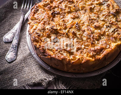 Hausgemachter Apfelkuchen mit Zimt und Nüssen auf Oliven Holzplatte, rustikalen Stil, selektiven Fokus Stockfoto