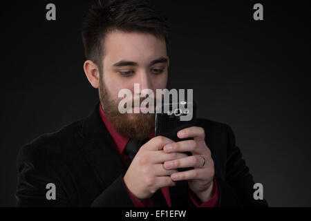 Ernste Geschäftsmann mit Hilfe seines Mobiltelefons Stockfoto