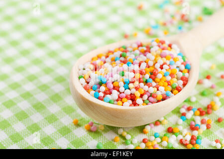 bunte Zucker Streusel in Holzlöffel auf Tischdecke Stockfoto