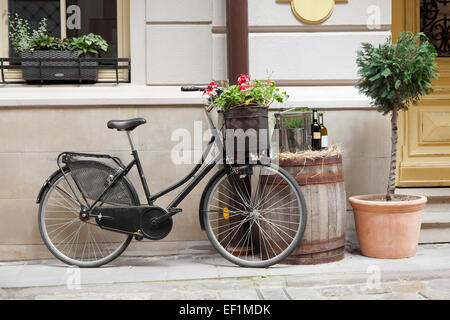 Altes Fahrrad tragen Blumen als Dekoration, Holzfass mit Flaschen Wein und Baum im Blumentopf Stockfoto