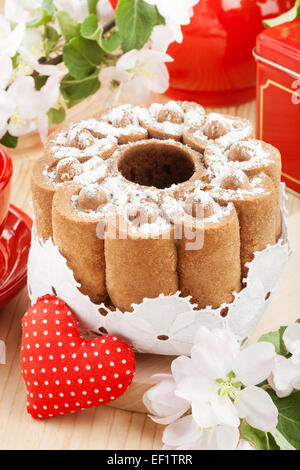 Kuchen mit roten Herzen und Zweige der Blüte Apfelbaum am Küchentisch Stockfoto