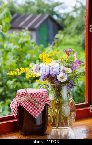 jede Menge Gartenblumen und Marmelade auf Fensterbank Stockfoto