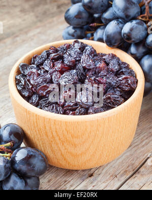 Rosinen in eine Schüssel geben und blauen Trauben auf alten rustikalen Holztisch Stockfoto