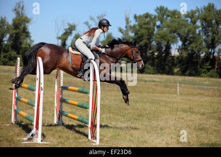 Mädchen im Pferdesport Uniform auf dem Pferderücken Hürde springen Stockfoto