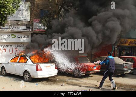 Kairo. 25. Januar 2015. Ein Mann gießt Wasser auf ein Auto in Brand gesetzt von Anhängern des gestürzten Präsidenten Ägyptens Mohamed Morsi bei Zusammenstößen mit der Polizei während einer Demonstration in Bezirk von Al Matarya, Ost-Kairo, Ägypten, am 25. Januar 2015, dem 4. Jahrestag des Aufstands Ägyptens ehemaliger Präsident Hosni Mubarak zu stürzen. © Ahmed Gomaa/Xinhua/Alamy Live-Nachrichten Stockfoto