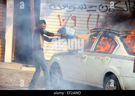 Kairo. 25. Januar 2015. Ein Mann gießt Wasser auf ein Auto in Brand gesetzt von Anhängern des gestürzten Präsidenten Ägyptens Mohamed Morsi bei Zusammenstößen mit der Polizei während einer Demonstration in Bezirk von Al Matarya, Ost-Kairo, Ägypten, am 25. Januar 2015, dem 4. Jahrestag des Aufstands Ägyptens ehemaliger Präsident Hosni Mubarak zu stürzen. © Ahmed Gomaa/Xinhua/Alamy Live-Nachrichten Stockfoto