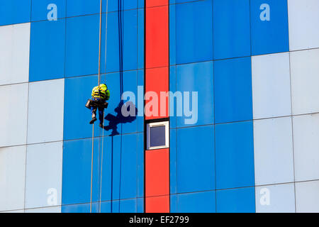 Workman, unterbrochen durch ein Seilgeschirr Reparatur von Schäden an der Außenwand eines mehrstöckigen Gebäudes, Glasgow, Schottland Stockfoto