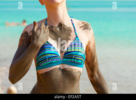 Junge hübsche Frau schmierte mit Schlamm am Strand Stockfoto