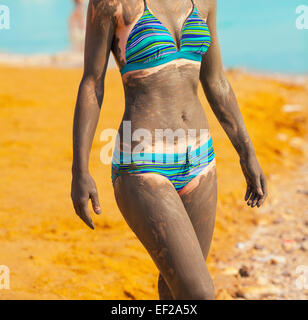 Junge hübsche Frau schmierte mit Schlamm am Strand Stockfoto