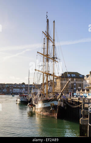 Ein Großsegler ist in Weymouth Hafen festgemacht Dock seitlich an einem sonnigen Tag mit blauem Himmel und sehr helle Wolke gesehen. Stockfoto