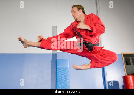 Ein Mann in einem Fitnessstudio einen Karate-Sprung zu tun Stockfoto