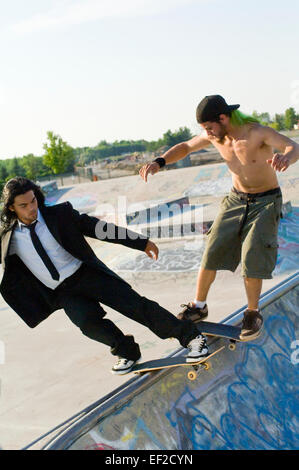 Zwei junge Männer, die über eine Rampe Skateboard Stockfoto