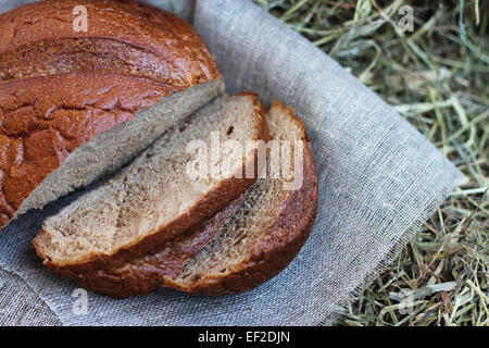 Braun frisch geschnittenem Brot und Flachs Textil auf Heu Stockfoto