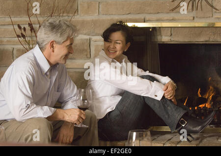 Reifen Sie paar entspannen zu Hause zusammen sitzen durch einen Kamin Stockfoto