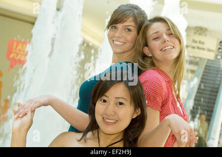 Drei Freunde von einem Brunnen in einem Einkaufszentrum Stockfoto