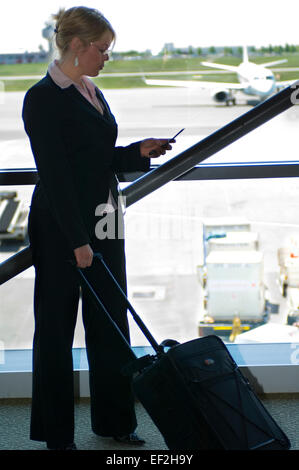 Geschäftsfrau im Flughafen mit Handy Stockfoto