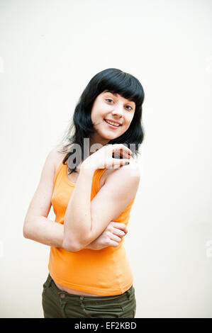 Mädchen stehen und Lächeln mit orange T-shirt auf weißem Hintergrund Stockfoto