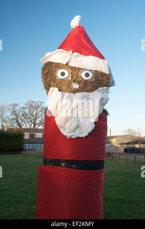 Happy Xmas. Eine große komische Figur des Santa Claus aus Heuballen. Es ist ein eigenwilliges Weihnachtszeit in der Landschaft von Dorset. England, UK. Stockfoto