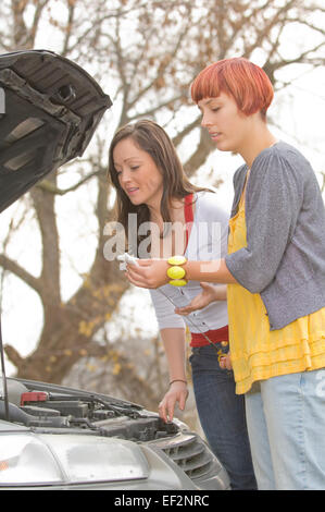 Zwei Frauen, die unter der Motorhaube des Autos Stockfoto