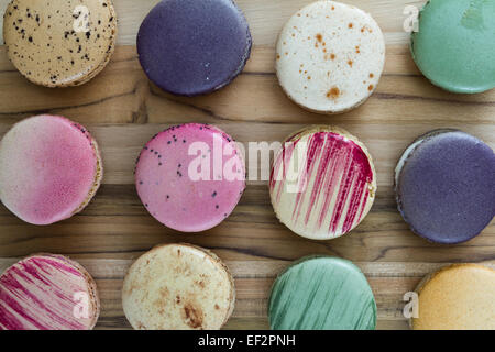 klassische französische Macarons handgefertigt und dekoriert in einer Vielzahl von Farben auf einem Holztisch Stockfoto