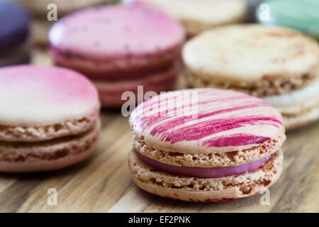 klassische französische Macarons handgefertigt und dekoriert in einer Vielzahl von Farben auf einem Holztisch Stockfoto