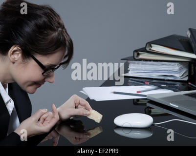 schöne Brünette Geschäftsfrau an ihrem Schreibtisch, die versuchen, ihre Computer-Maus mit Käse trap Stockfoto