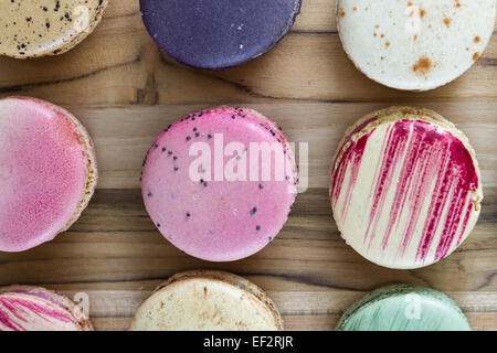 klassische französische Macarons handgefertigt und dekoriert in einer Vielzahl von Farben auf einem Holztisch Stockfoto
