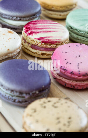 klassische französische Macarons handgefertigt und dekoriert in einer Vielzahl von Farben auf einem Holztisch Stockfoto