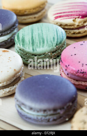 klassische französische Macarons handgefertigt und dekoriert in einer Vielzahl von Farben auf einem Holztisch Stockfoto