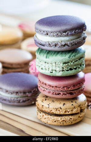klassische französische Macarons handgefertigt und dekoriert in einer Vielzahl von Farben auf einem Holztisch Stockfoto