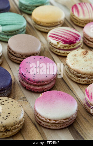 klassische französische Macarons handgefertigt und dekoriert in einer Vielzahl von Farben auf einem Holztisch Stockfoto